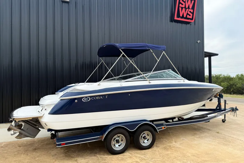 Slide: The Image of 2005 Cobalt 240 boat on trailer, blue and white, parked outside a building. - 12
