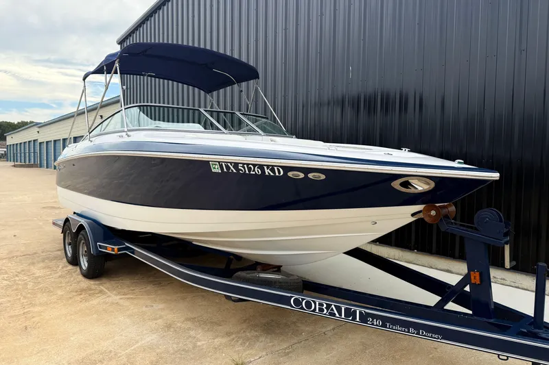 Slide: The Image of 2005 Cobalt 240 boat on trailer, parked near storage units. - 2