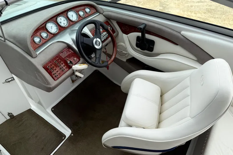 Slide: The Image of 2005 Cobalt 240 boat interior with white captain's chair and wood-accented dashboard. - 6