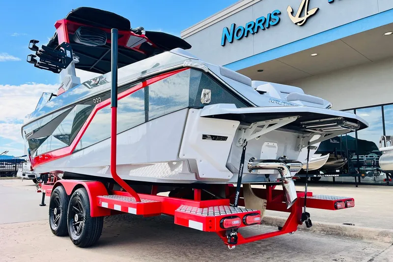 Slide: The Image of 2026 Nautique Super Air Nautique G25 boat on red trailer outside dealership. - 10