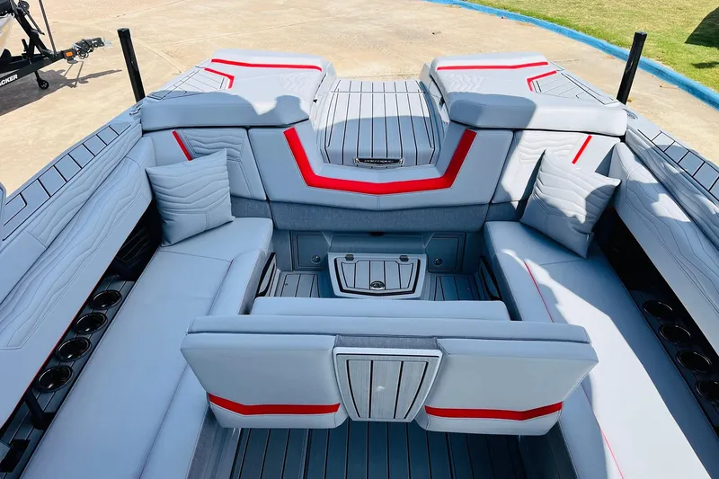 Slide: The Image of 2026 Nautique Super Air Nautique G25 interior with gray and red seating, cup holders, and cushions. - 46
