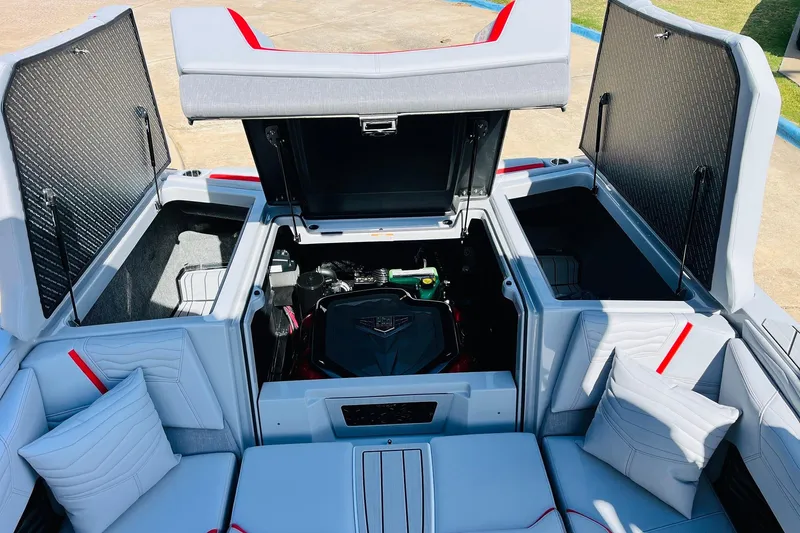 Slide: The Image of 2026 Nautique Super Air Nautique G25 engine compartment with open storage hatches and seating. - 76