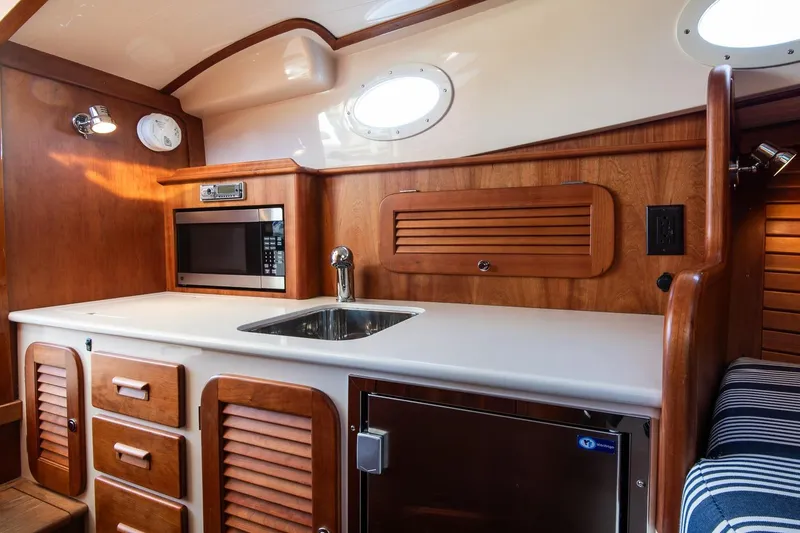 Slide: The Image of 2013 Hinckley Talaria 34 yacht interior with wooden cabinetry and modern kitchen amenities. - 25