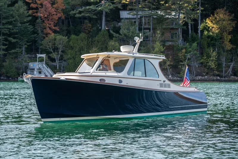 Slide: The Image of 2013 Hinckley Talaria 34 yacht on serene lake with forested backdrop. - 3