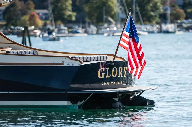 Slide: The Image of 2013 Hinckley Talaria 34 boat with American flag, named "Glory," on calm water. - 5