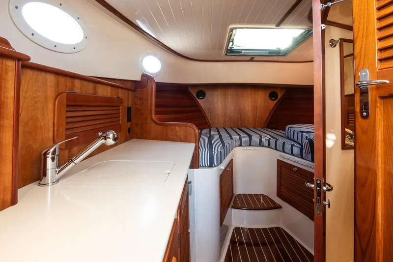 Slide: The Image of 2013 Hinckley Talaria 34 interior with wood finish and striped bedding. - 18