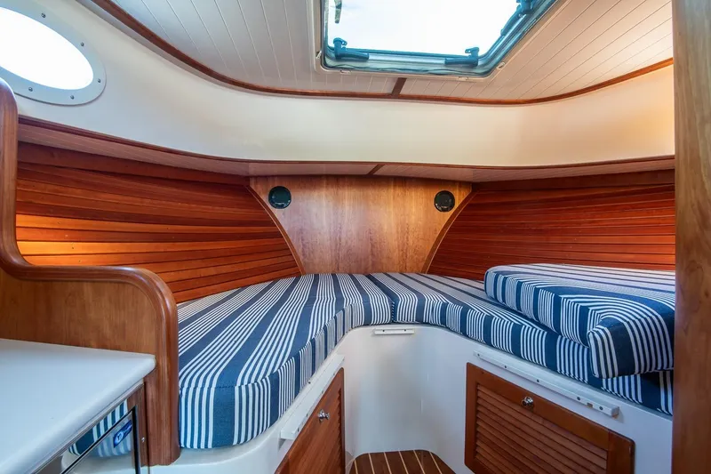Slide: The Image of 2013 Hinckley Talaria 34 cabin interior with striped cushions and wooden paneling. - 24