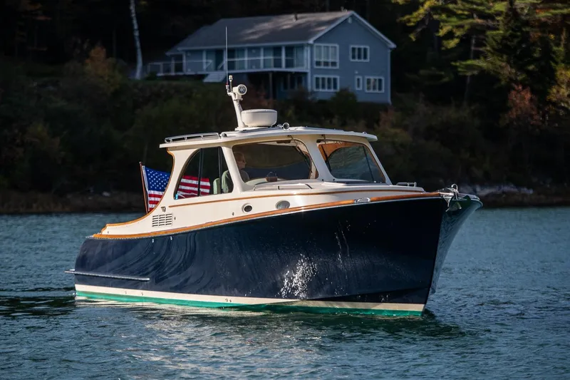 Slide: The Image of 2013 Hinckley Talaria 34 boat on serene water with a house in the background. - 29