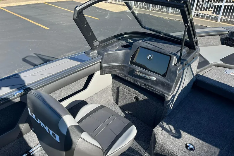 Slide: The Image of 2026 Lund 1875 Crossover XS boat deck with motor, gray carpet, and storage compartments. - 11