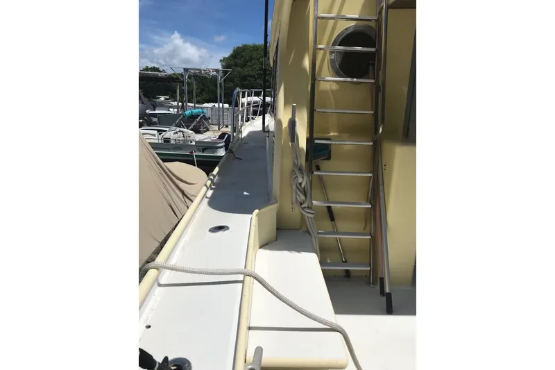 Slide: The Image of 1999 Custom Sport Fishing boat deck with ladder and docked boats in background. - 18