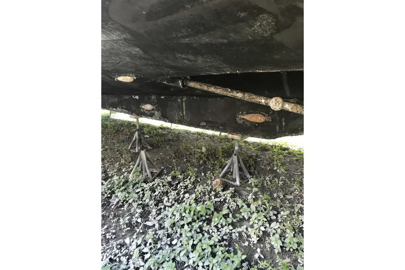 Slide: The Image of Underside of a 1999 Custom Sport Fishing boat on stands, showing propeller shaft. - 29