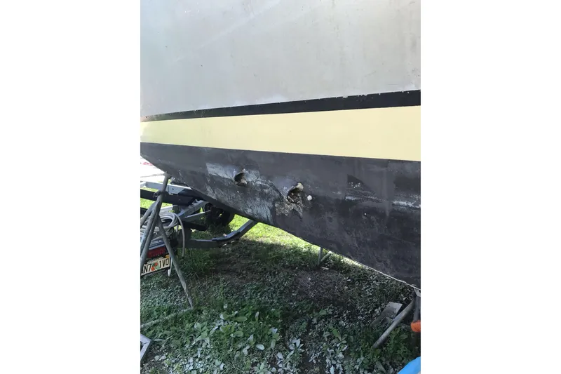 Slide: The Image of Damaged hull of a 1999 Custom Sport Fishing boat on a trailer. - 30