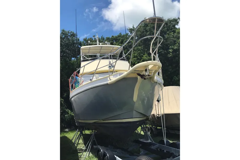 Slide: The Image of Custom 1999 Sport Fishing boat on trailer, surrounded by trees under a blue sky. - 7