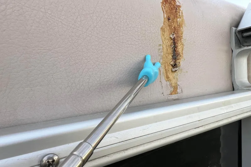 Slide: The Image of Damaged upholstery on 2013 Godfrey Sweetwater 2286 boat with blue tool pointing at tear. - 22