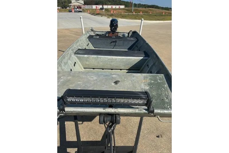 Slide: The Image of 1981 Lowe L1448 Jon boat with light bar, parked on concrete surface. - 2