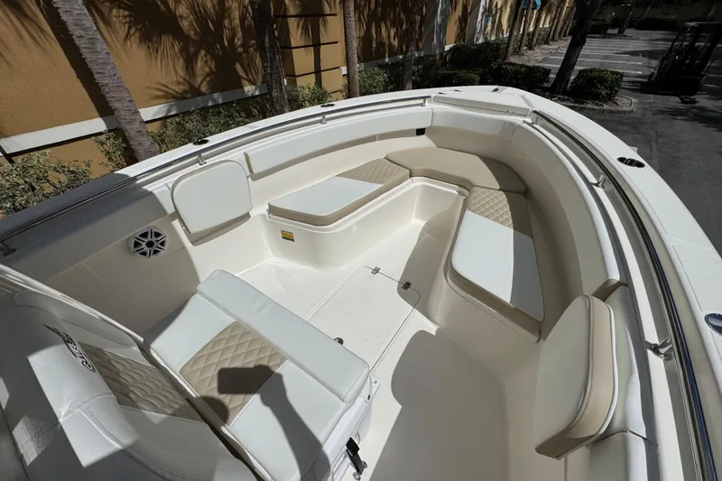 Slide: The Image of 2026 Bulls Bay 255CC boat interior with cushioned seating and speaker, parked outdoors. - 20