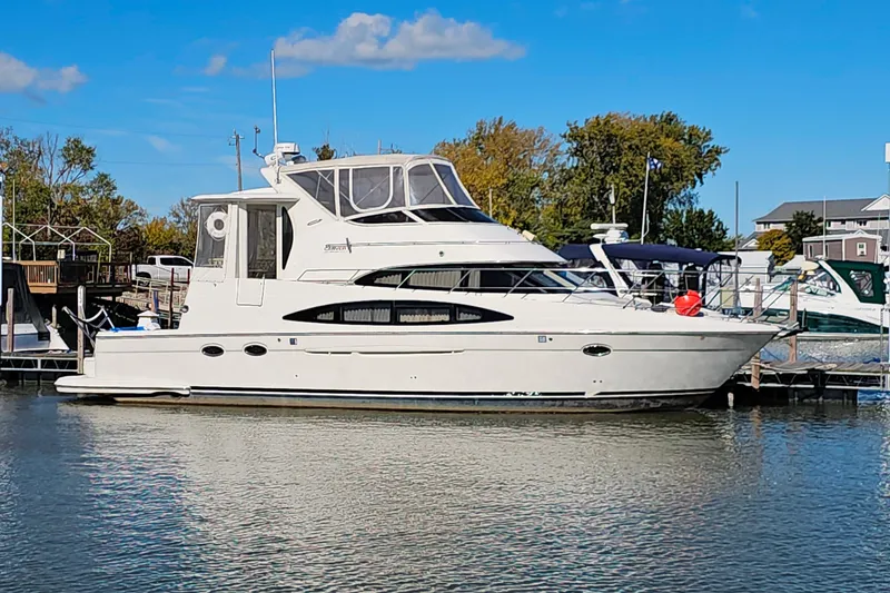 The Image of 2004 Carver 444 Cockpit Motor Yacht docked in a marina under a clear blue sky. - 0