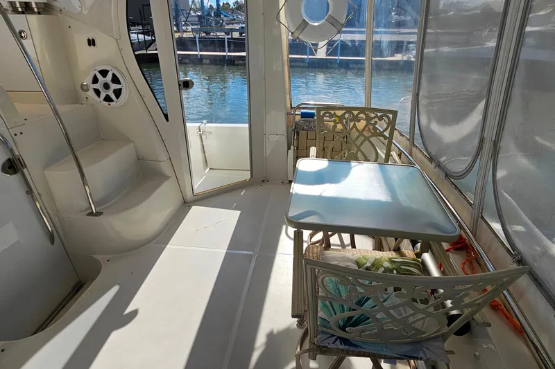 Slide: The Image of 2004 Carver 444 Cockpit Motor Yacht interior with table, chairs, and marina view. - 11