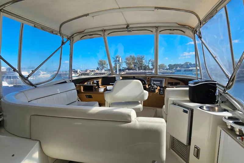 Slide: The Image of 2004 Carver 444 Cockpit Motor Yacht interior with helm, seating, and marina view. - 13