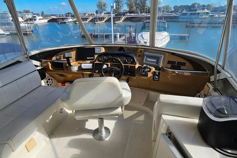 Slide: The Image of 2004 Carver 444 Cockpit Motor Yacht helm with modern navigation equipment and marina view. - 14