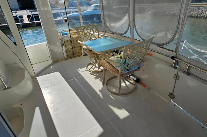 Slide: The Image of 2004 Carver 444 Cockpit Motor Yacht interior with table and chairs, docked by the water. - 12