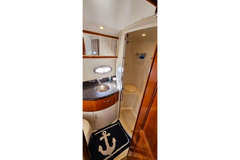 Slide: The Image of 2004 Carver 444 Cockpit Motor Yacht bathroom with sink, shower, and nautical-themed rug. - 44