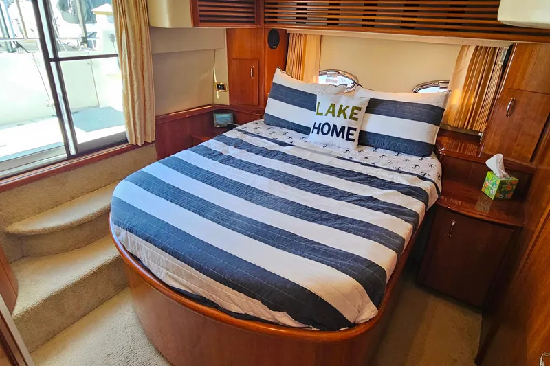 Slide: The Image of 2004 Carver 444 Cockpit Motor Yacht bedroom with striped bedding and "Lake Home" pillow. - 45