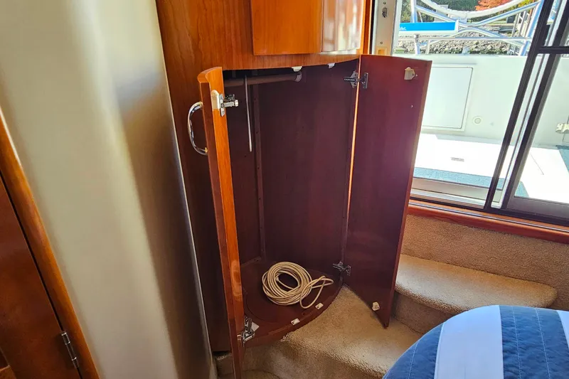 Slide: The Image of Open wooden cabinet inside 2004 Carver 444 Cockpit Motor Yacht, with coiled rope inside. - 48