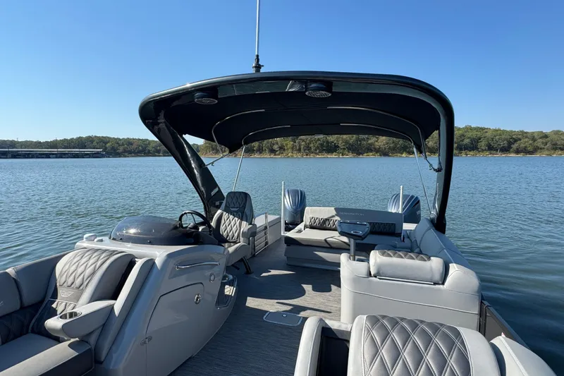 Slide: The Image of 2023 Bennington QX 27 QXSBAX2 pontoon boat on a serene lake. - 14