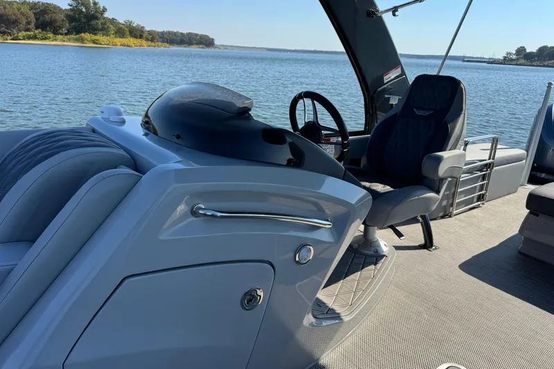Slide: The Image of 2023 Bennington QX 27 QXSBAX2 boat interior with steering wheel, luxurious seating, and water view. - 17