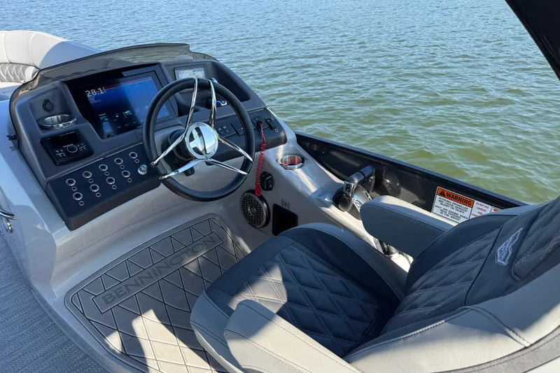 Slide: The Image of 2023 Bennington QX 27 QXSBAX2 boat dashboard with steering wheel and controls on water. - 19