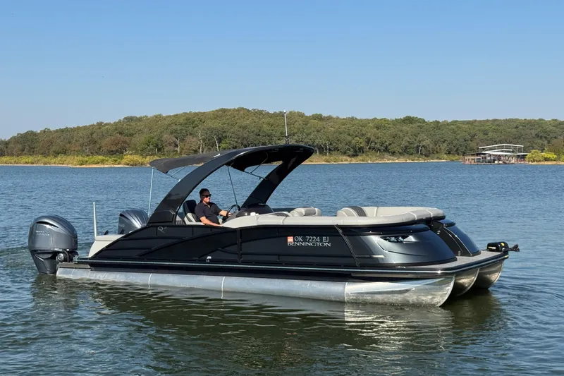 Slide: The Image of 2023 Bennington QX 27 QXSBAX2 pontoon boat on a serene lake. - 6