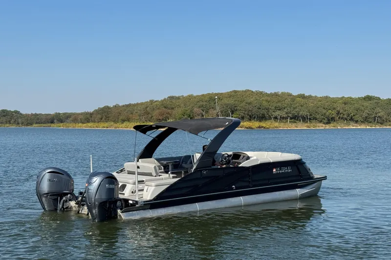 Slide: The Image of 2023 Bennington QX 27 QXSBAX2 pontoon boat on a serene lake. - 8