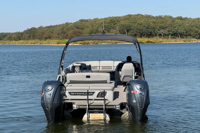 Slide: The Image of 2023 Bennington QX 27 QXSBAX2 pontoon boat on a serene lake. - 9