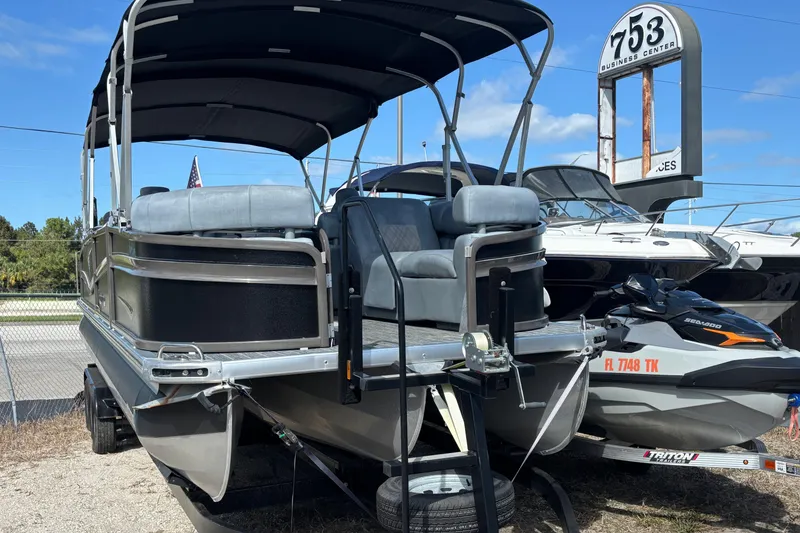 Slide: The Image of 2021 Premier 270 Intrigue RF pontoon boat with canopy, parked near other boats and a jet ski. - 3