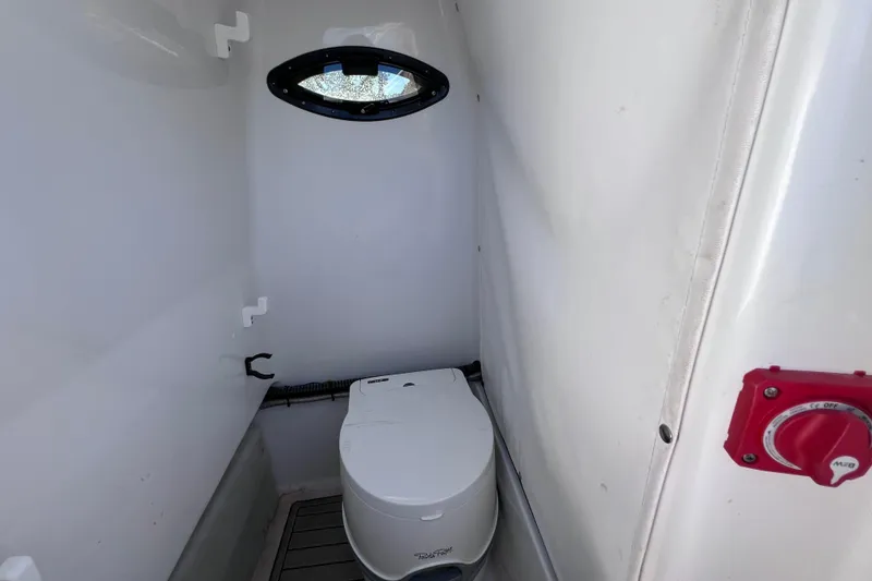 Slide: The Image of 2023 Sportsman Open 242 Center Console boat interior with compact marine toilet. - 46