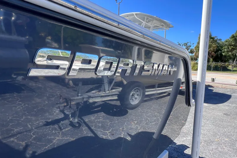Slide: The Image of 2023 Sportsman Open 242 Center Console boat with reflective logo in sunny outdoor setting. - 5