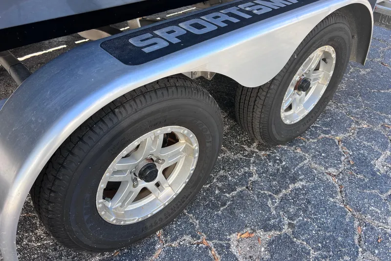 Slide: The Image of 2023 Sportsman Open 242 Center Console trailer wheels on asphalt surface. - 53