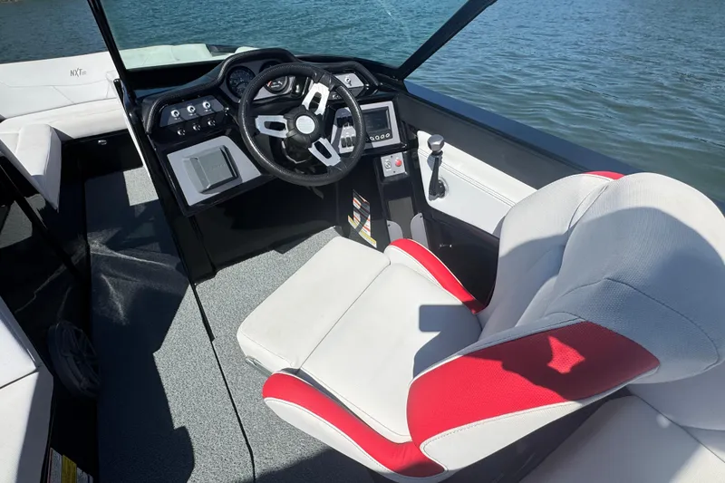 Slide: The Image of 2021 MasterCraft NXT24 boat interior with steering wheel and red-accented captain's chair. - 15