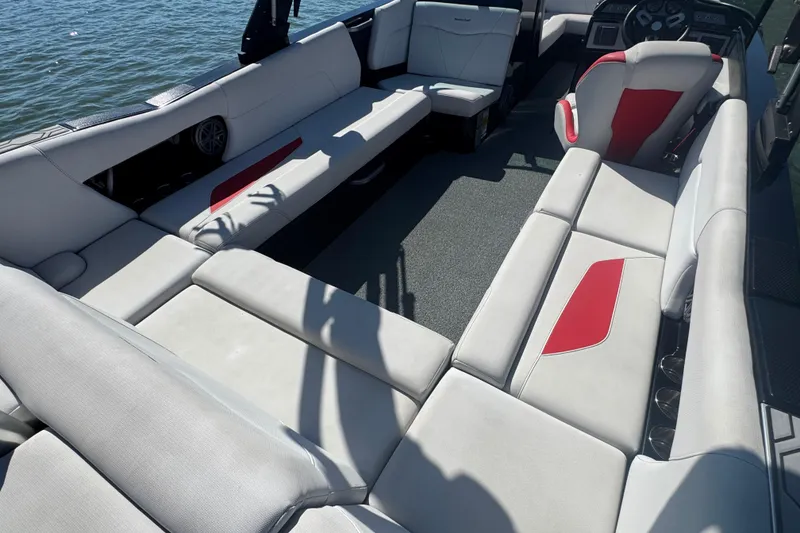 Slide: The Image of 2021 MasterCraft NXT24 boat interior with spacious seating and red accents on the water. - 22