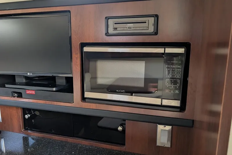 Slide: The Image of Interior of 2016 Chaparral 290 Signature with TV and microwave in wooden cabinetry. - 22