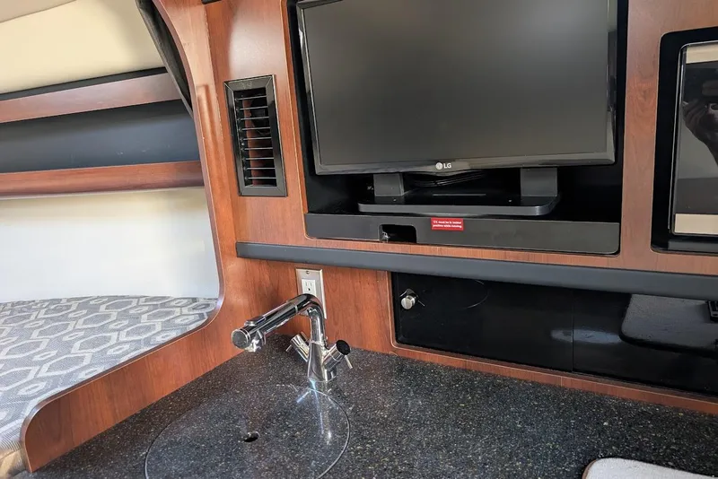 Slide: The Image of 2016 Chaparral 290 Signature interior with TV, sink, and seating area. - 24