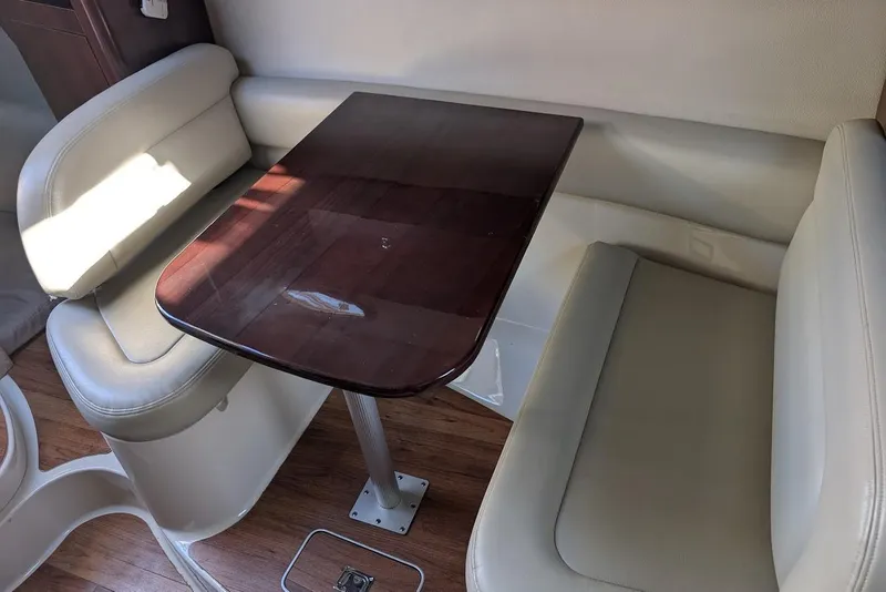 Slide: The Image of Interior of 2016 Chaparral 290 Signature boat with wooden table and cushioned seating. - 25
