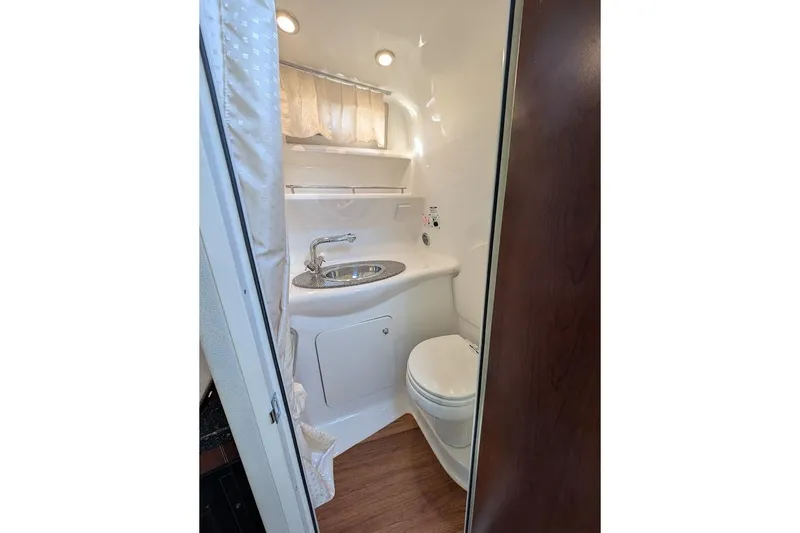 Slide: The Image of 2016 Chaparral 290 Signature boat bathroom with sink, toilet, and wood accents. - 27