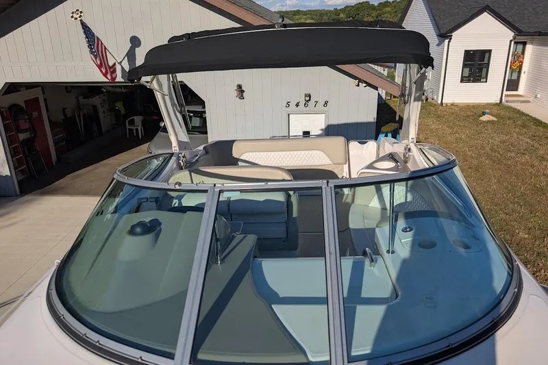 Slide: The Image of 2016 Chaparral 290 Signature boat with black canopy, parked near a garage. - 7
