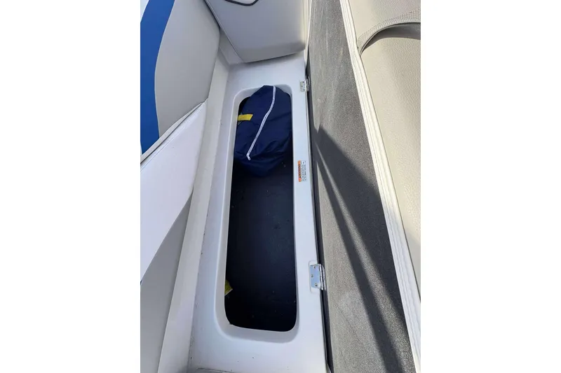 Slide: The Image of 2022 Starcraft Crossover 211 SCX OB boat storage compartment with blue bag inside. - 13
