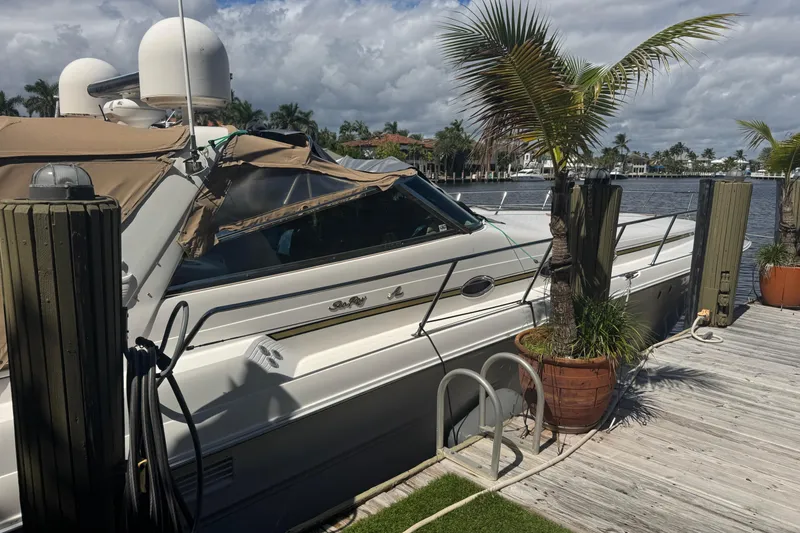 Slide: The Image of 1995 Sea Ray 500 Sundancer yacht docked by palm trees under cloudy sky. - 3