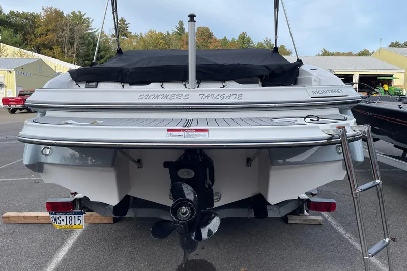 Slide: The Image of 2023 Monterey 224FS boat with covered deck, ladder, and visible propeller in a parking area. - 2