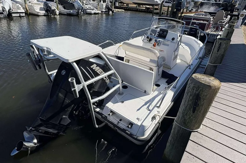 Slide: The Image of 2011 Boston Whaler 180 Dauntless boat docked, featuring a Mercury outboard motor. - 18