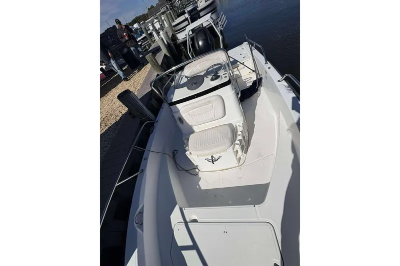 Slide: The Image of 2011 Boston Whaler 180 Dauntless boat docked at marina, featuring spacious deck and seating. - 4